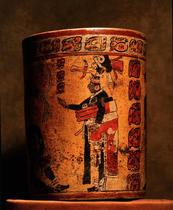 Cylindrical vessel decorated with date glyphs and a Mayan ball player wearing black body paint and heavy padding for the competition.