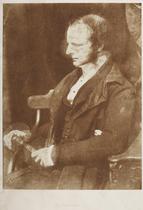 Half-length seated portrait of Rev. James Scott (c. 1800-1864), in left profile, holding a book in his lap. A portrait from a volume of calotype images and portraits. Early photographic technique also